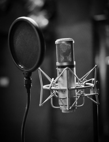 grayscale photo of condenser microphone beside pop filter