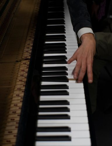 a person sitting at a piano with their hand on the keys